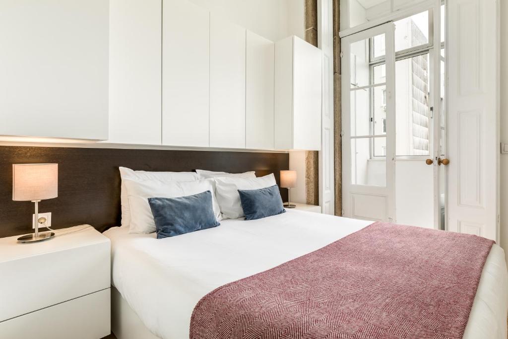 a bedroom with a large white bed with blue pillows at Apartment Bolhao Market by Sweet Porto in Porto