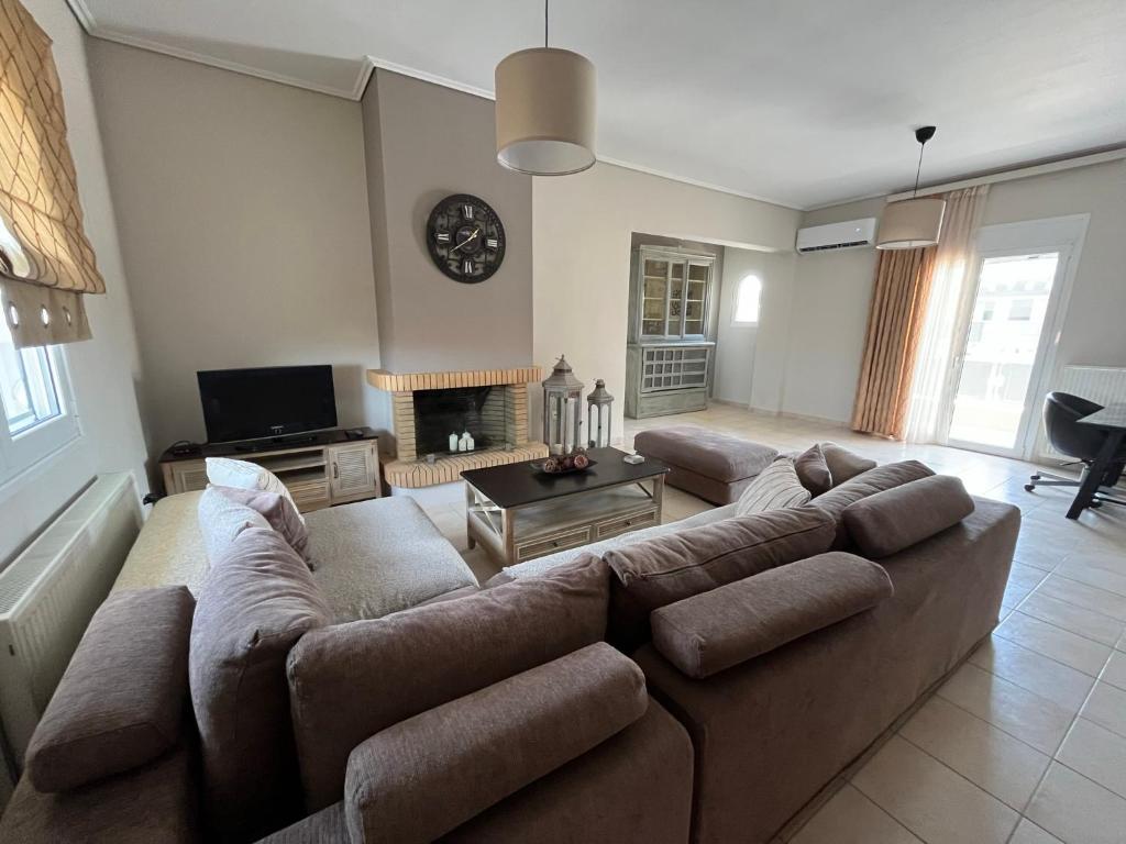 a living room with a large couch and a fireplace at ILION Air Host - near Athens International Airport in Markopoulo