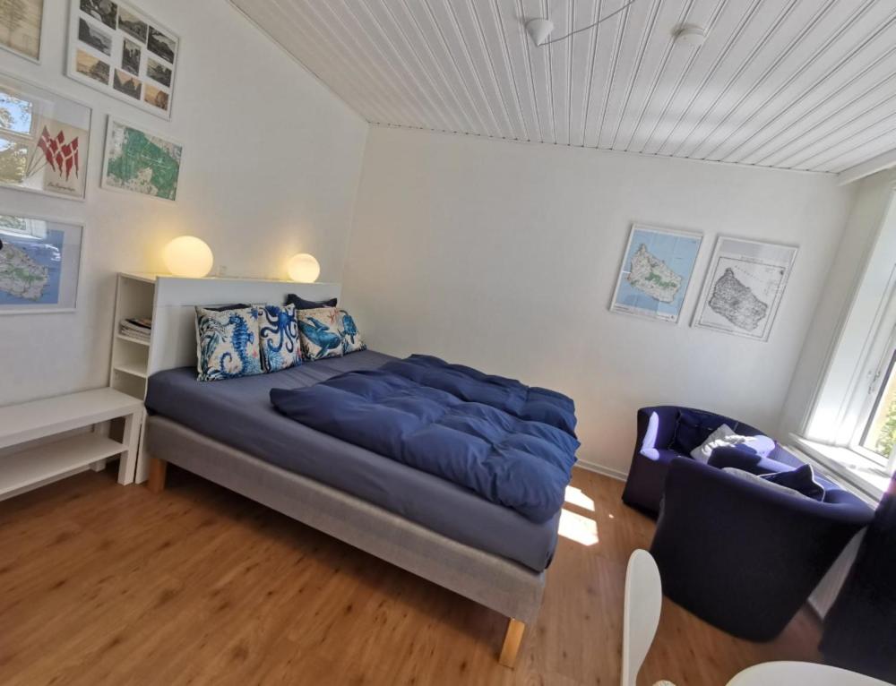 a bedroom with a blue bed and a chair at The Cherry Apartment - 'Den Gule Svane' Guest House near Rønne & Beach in Rønne