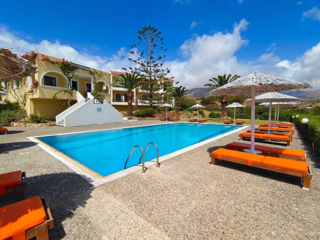 una piscina con sedie arancioni e ombrelloni di Alex a Karpathos