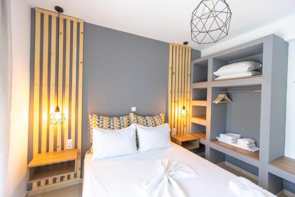 Schlafzimmer mit einem weißen Bett und Holzregalen in der Unterkunft SK Suites Thassos in Skala Potamias