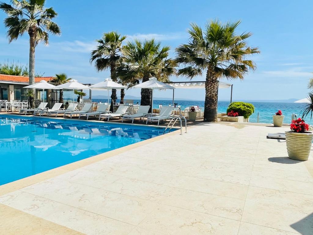 a swimming pool with chairs and the ocean in the background at Afitis Boutique Hotel in Afitos