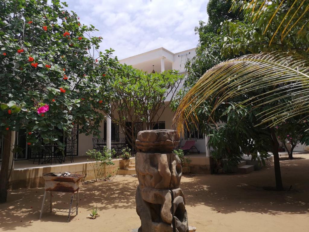 a statue in a courtyard with trees and a building at Keur Baboune in Mbour