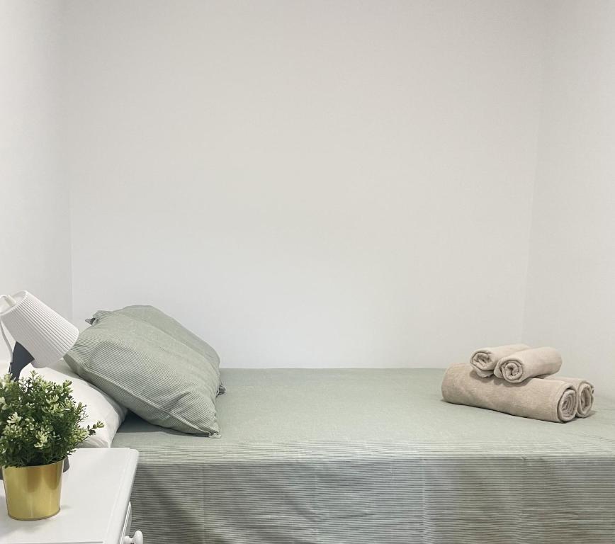 ein Bett mit Handtüchern und einer weißen Wand in der Unterkunft Apartamento el Cim, al centro de Arbúcies in Arbúcies