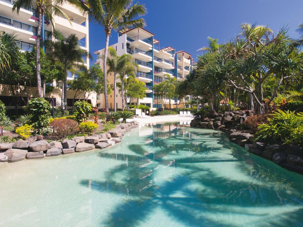 a swimming pool at a resort with palm trees at Oaks Sunshine Coast Seaforth Resort in Alexandra Headland