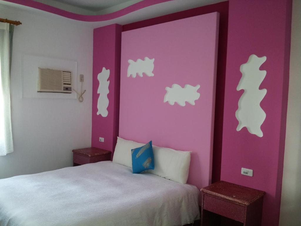 a bedroom with a bed with purple and white walls at Country Kos Hostel in Kenting