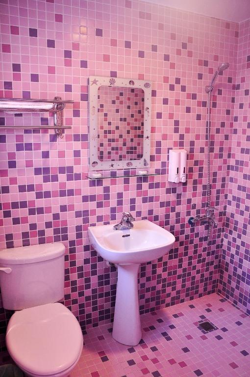 a pink tiled bathroom with a toilet and a sink at Country Kos Hostel in Kenting