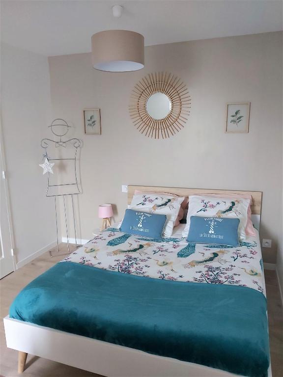 une chambre avec un lit avec des oreillers bleus et un miroir dans l'établissement Studio DUNE- Côte de GRANIT ROSE, à Ploubezre