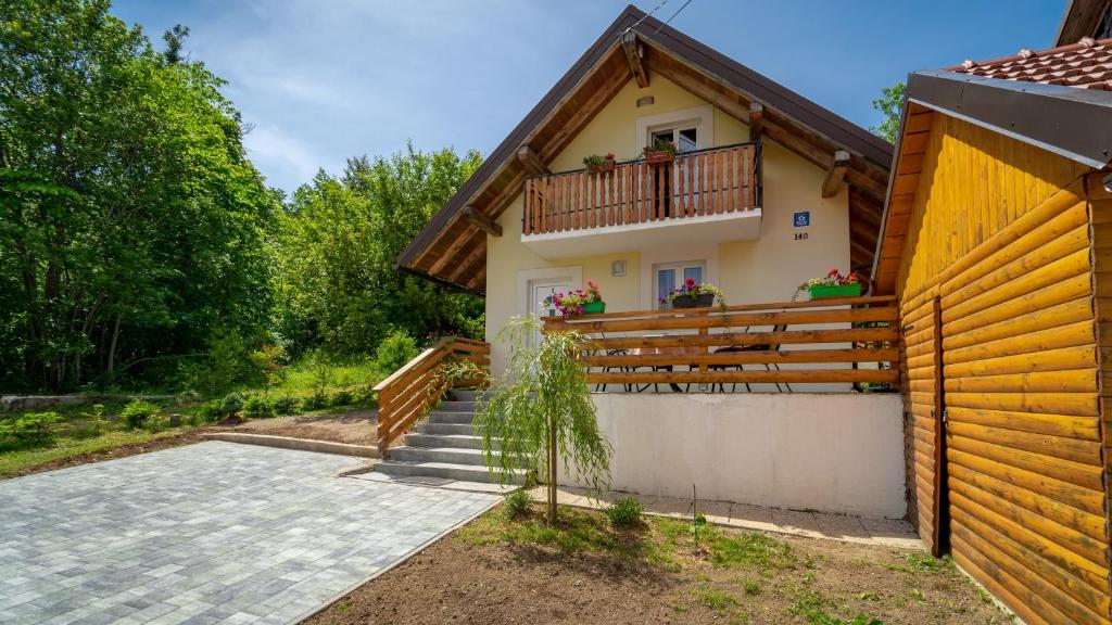 a house with a balcony and a wooden fence at Holiday Home Kokot in Ravna Gora