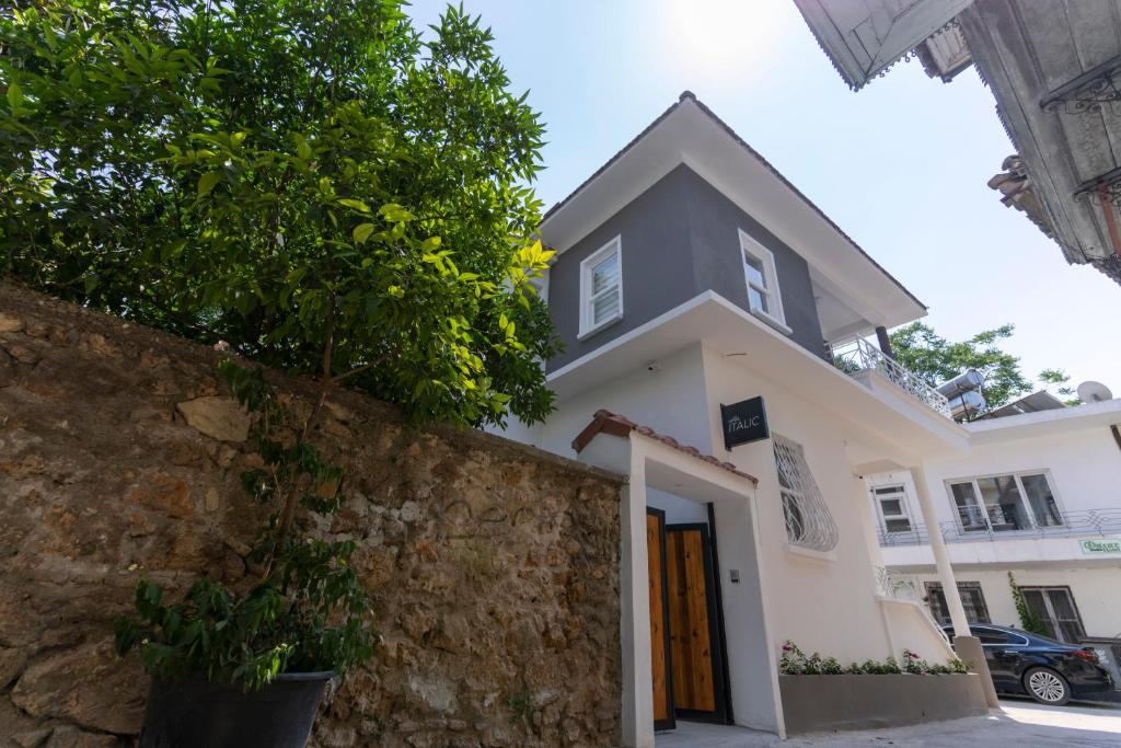 a white house with a stone wall and a tree at Villa Italic in Antalya