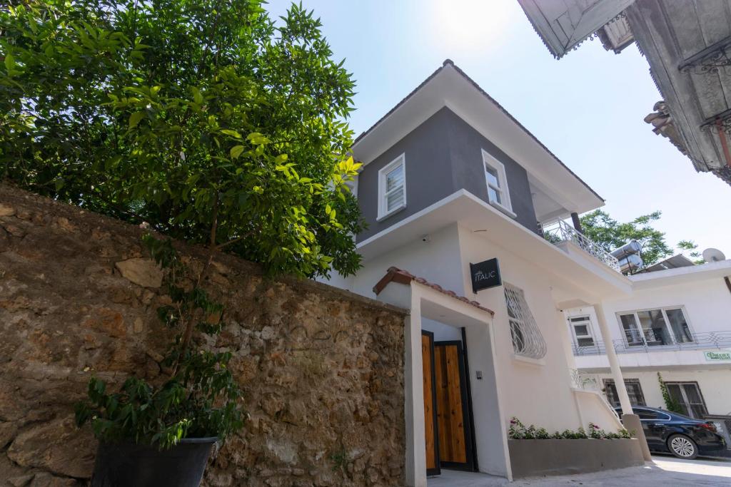 uma casa branca com uma parede de pedra e uma árvore em Villa Italic em Antalya