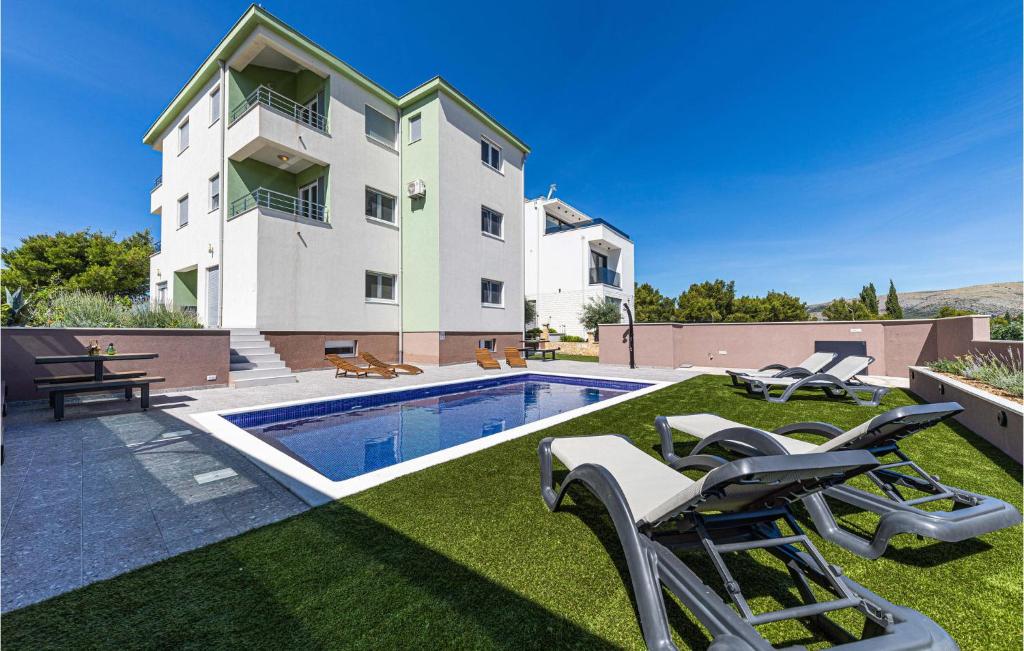 a villa with a swimming pool in front of a building at Stunning Apartment In Saldun With 2 Bedrooms, Wifi And Outdoor Swimming Pool in Trogir
