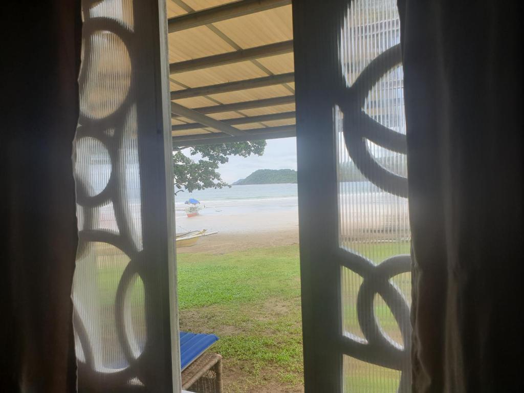 a window view of the beach from a house at Tupi's Beachfront Home 2BR in Bacungan