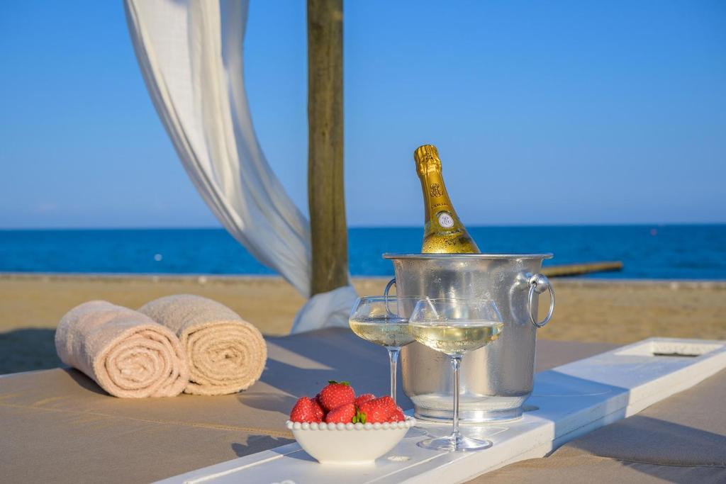 a table with a bottle of champagne and a bowl of strawberries at Pareus Beach Resort in Caorle