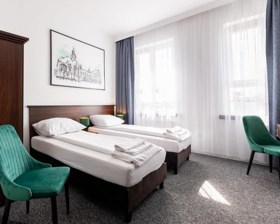 Cette chambre d'hôtel comprend deux lits et une chaise verte. dans l'établissement Hotel i Restauracja Nad Jeziorem, à Człuchów