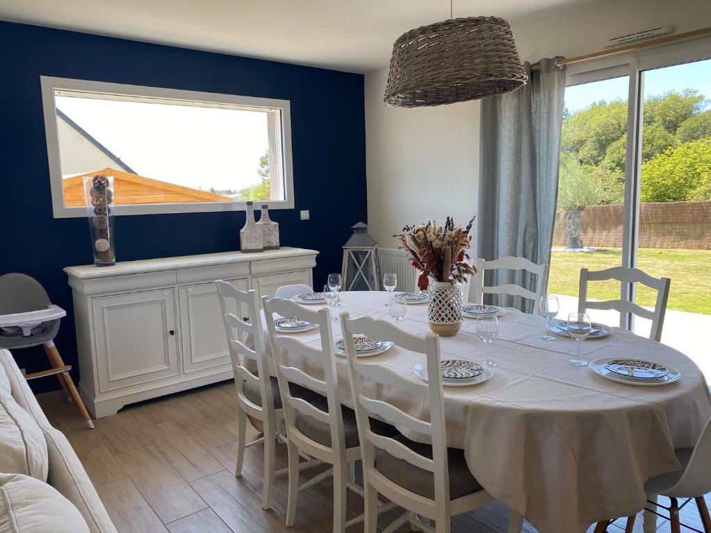 une salle à manger avec une table et des chaises blanches dans l'établissement Maison calme familiale proche plages, à Erquy