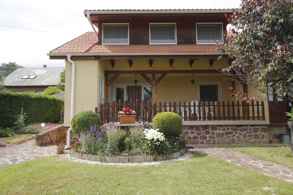 a house with a porch with a fence and flowers at Beautiful accommodation with garden in Balatonszepezd