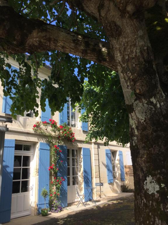 a building with blue doors and flowers on it at Entre Vignobles et Estuaire - Gîte 12 pers in Saint-Thomas-de-Cônac