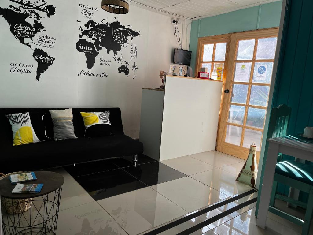 a living room with a black couch and a world map on the wall at Hostal Avenue in La Serena
