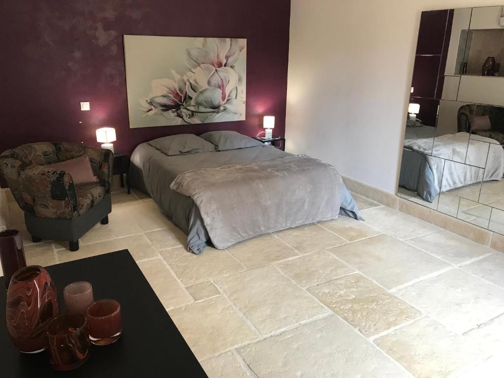 1 dormitorio con cama, silla y espejo en Gîtes du Noyer, en Praslay