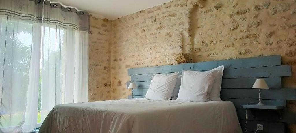 a bedroom with a bed with a blue headboard and a window at Le Petit Pré in Bouesse