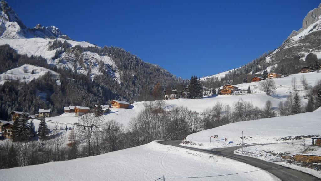 une montagne enneigée avec une route au premier plan dans l'établissement Apartment Residence Les Alpages, à La Giettaz