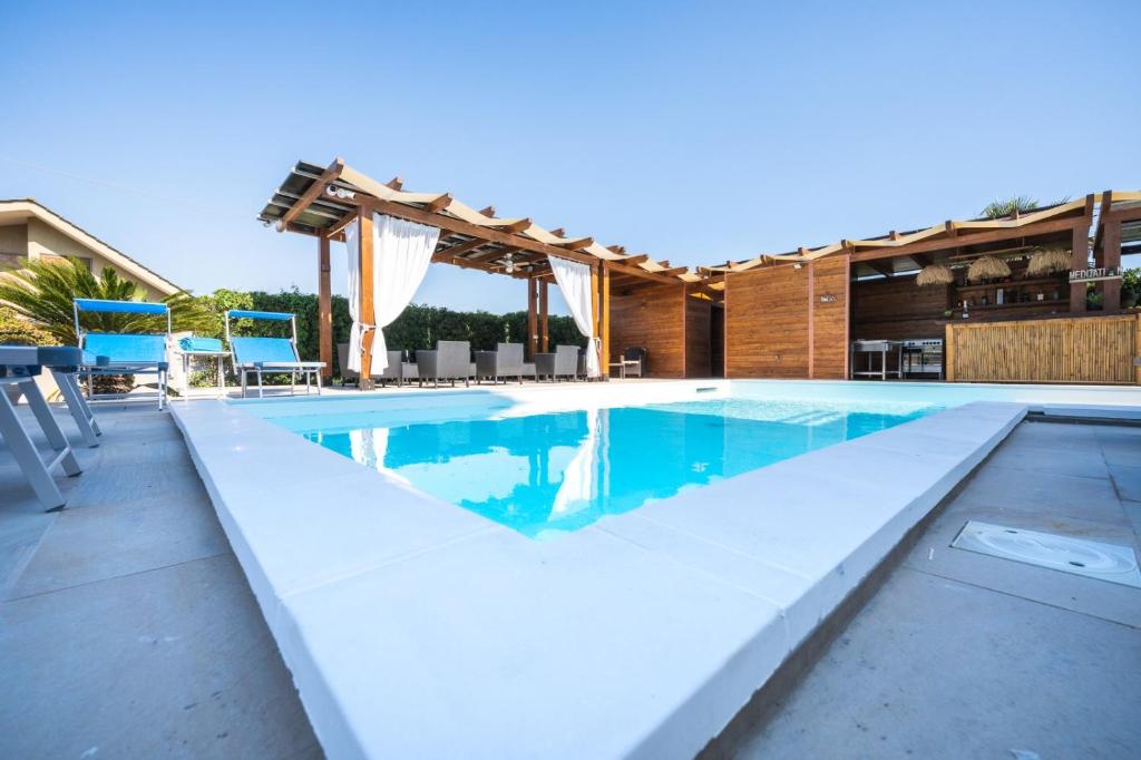 - une piscine avec des chaises bleues à côté d'une maison dans l'établissement Stampeggioni Appartamenti, à Anzio