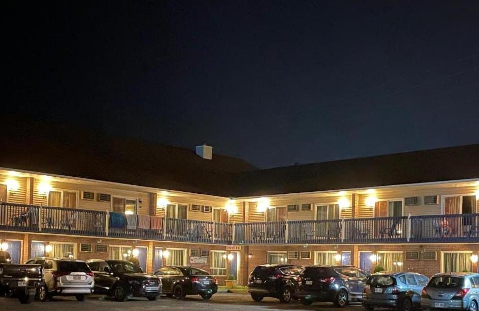 een gebouw met auto's geparkeerd op een parkeerplaats 's nachts bij Hotel Motel Granby in Granby