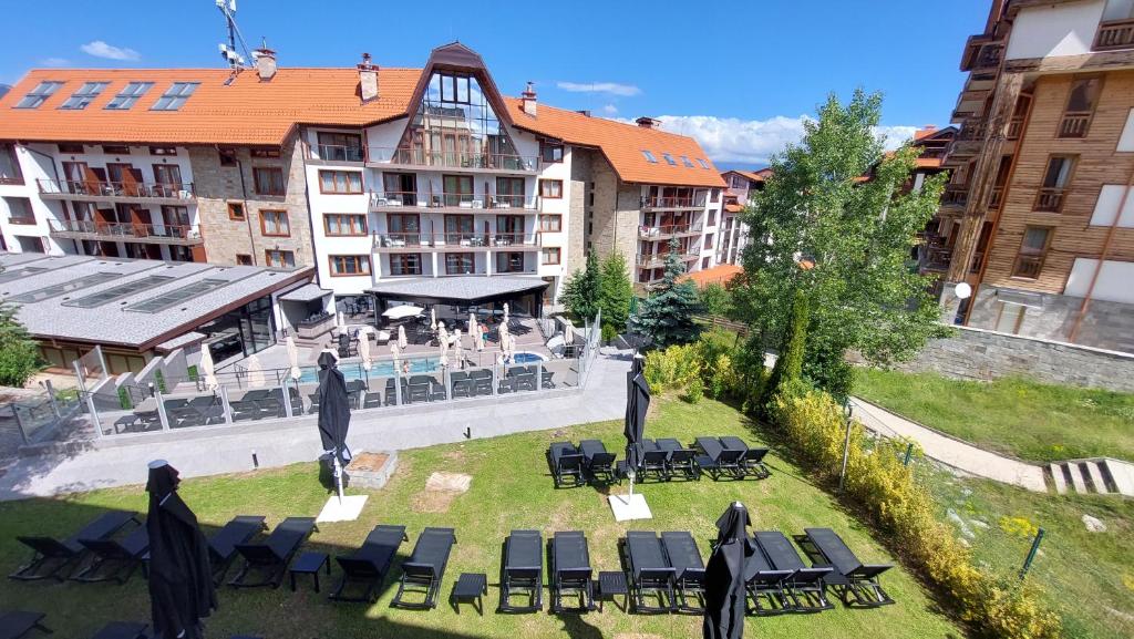 a group of chairs and tables in a yard with buildings at Free SPA в Св. Иван Рилски - Сладък дом сред лукс in Bansko