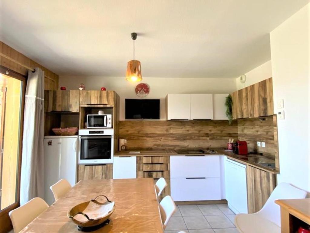 eine Küche mit weißen Schränken und einer Holzwand in der Unterkunft Chalet La Joue du Loup, 3 pièces, 7 personnes - FR-1-504-70 in Le Dévoluy