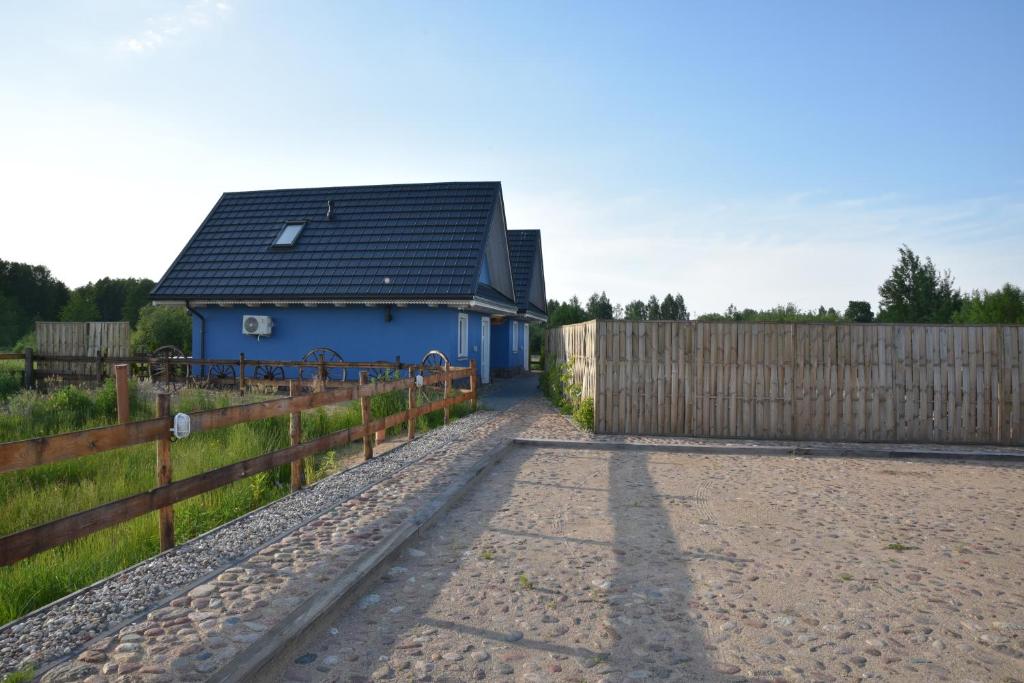 niebieski dom z płotem obok drogi gruntowej w obiekcie Diedushka Noclegi w Białowieży