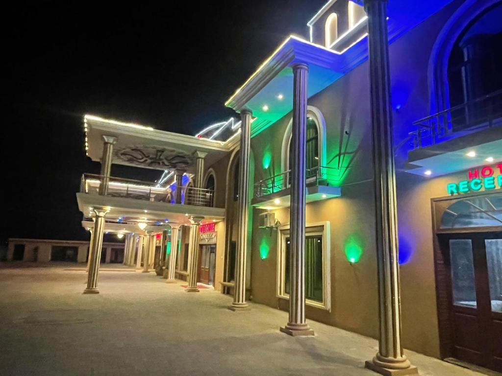 Mughal E Azam Hotel في Liāquatpur: مجموعة من المباني ذات الأضواء الخضراء والأزرق