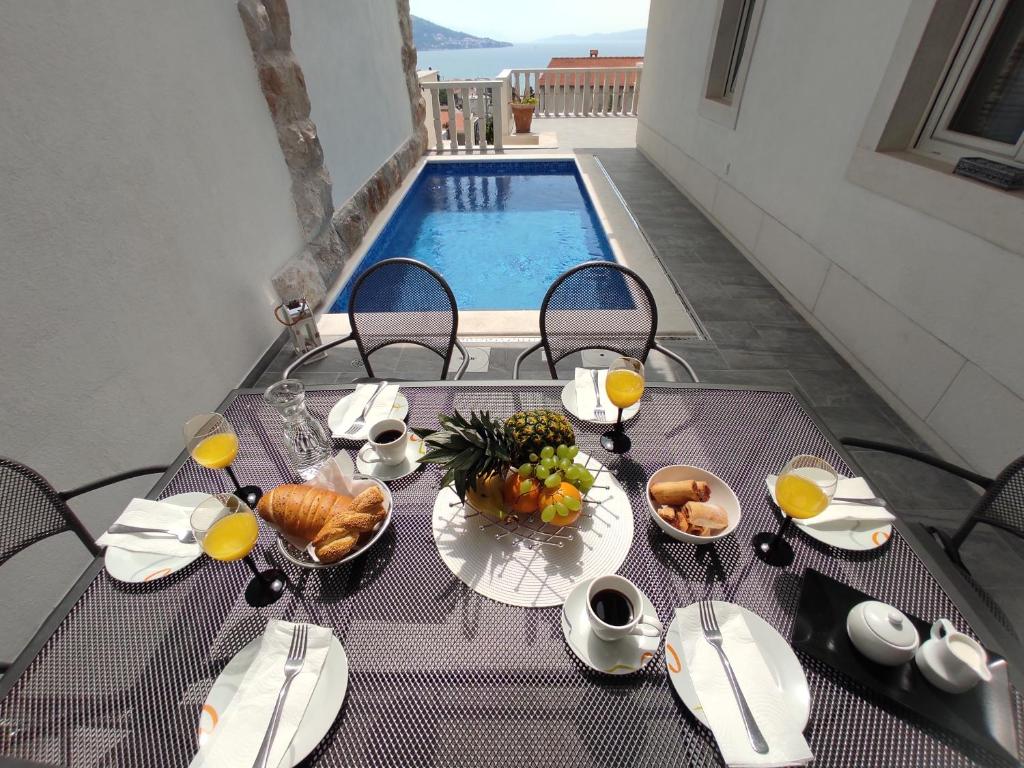 a table with a plate of food and fruit on it at Apartment Valentina - private pool,200m from beach in Omiš