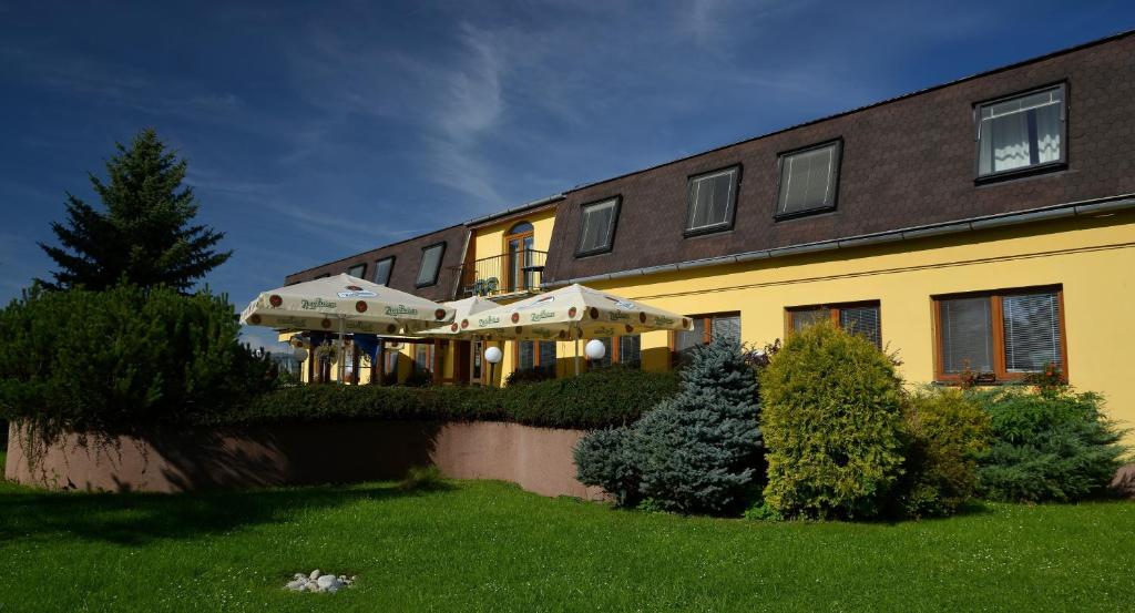 a yellow building with two umbrellas in front of it at Penzion Agrothermal in Bešeňová