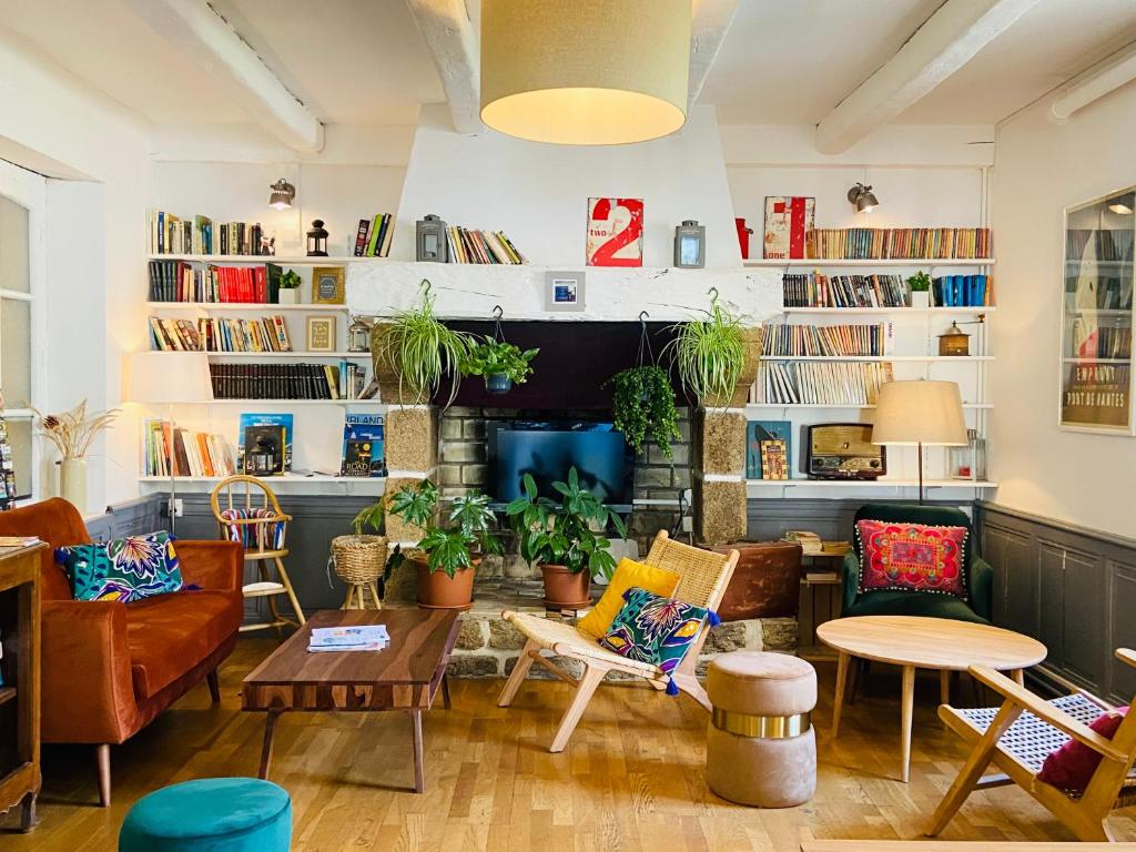 een woonkamer met stoelen, tafels en boekenplanken bij Hotel Saint-Michel in Dinard