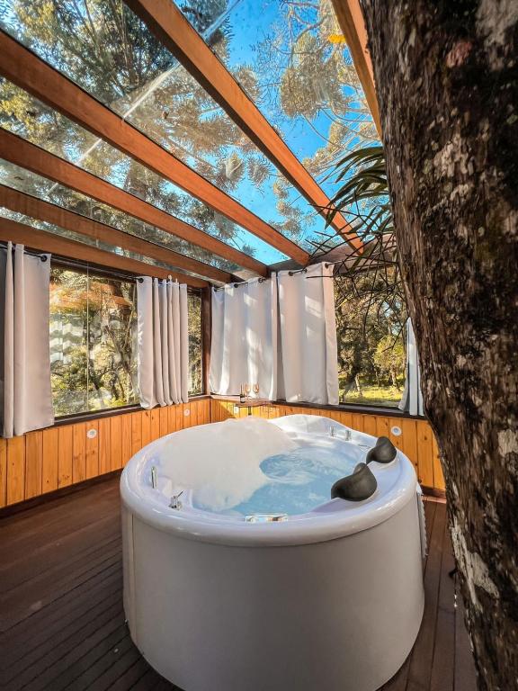 a bath tub in a room with a tree at Estalagem Monte Verde in Monte Verde