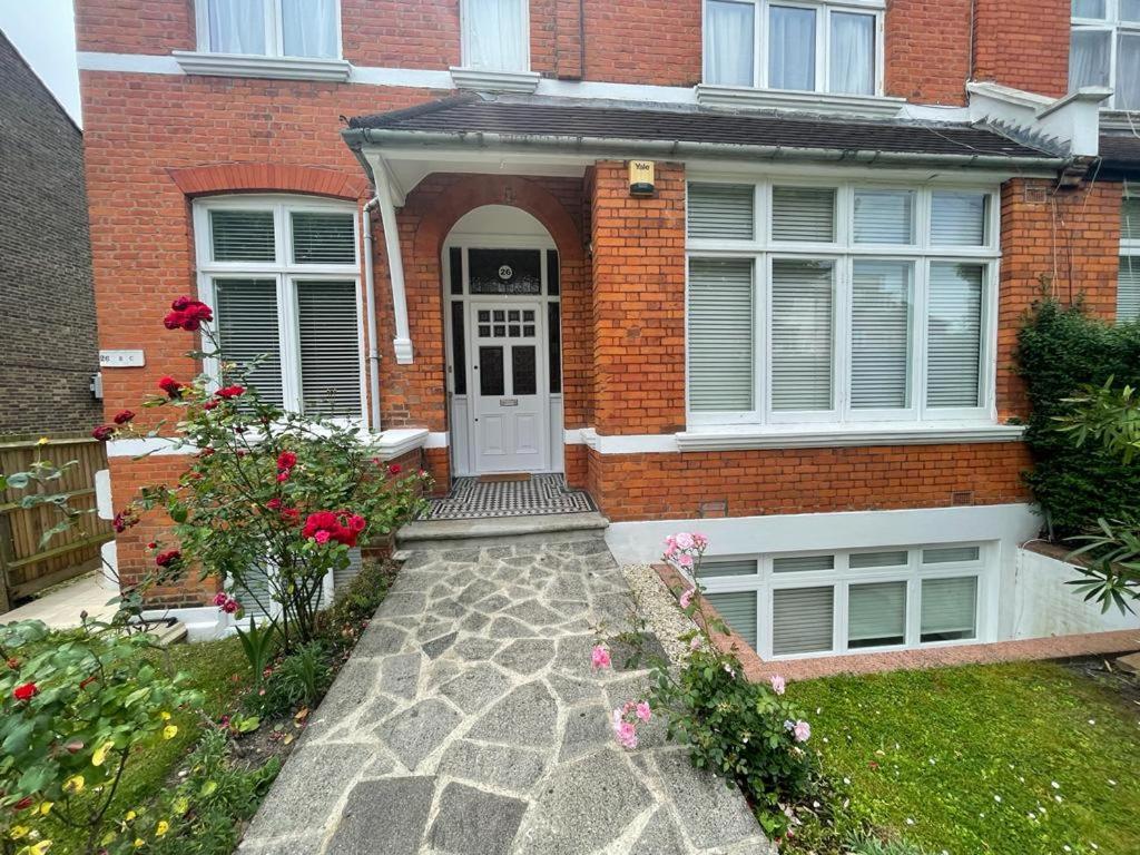 a brick house with a white door and flowers at Spacious Holiday Home! in London