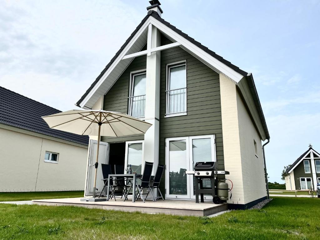 ein kleines Haus mit einem Tisch und einem Sonnenschirm in der Unterkunft Ferienhaus Fischkopf in Büsum