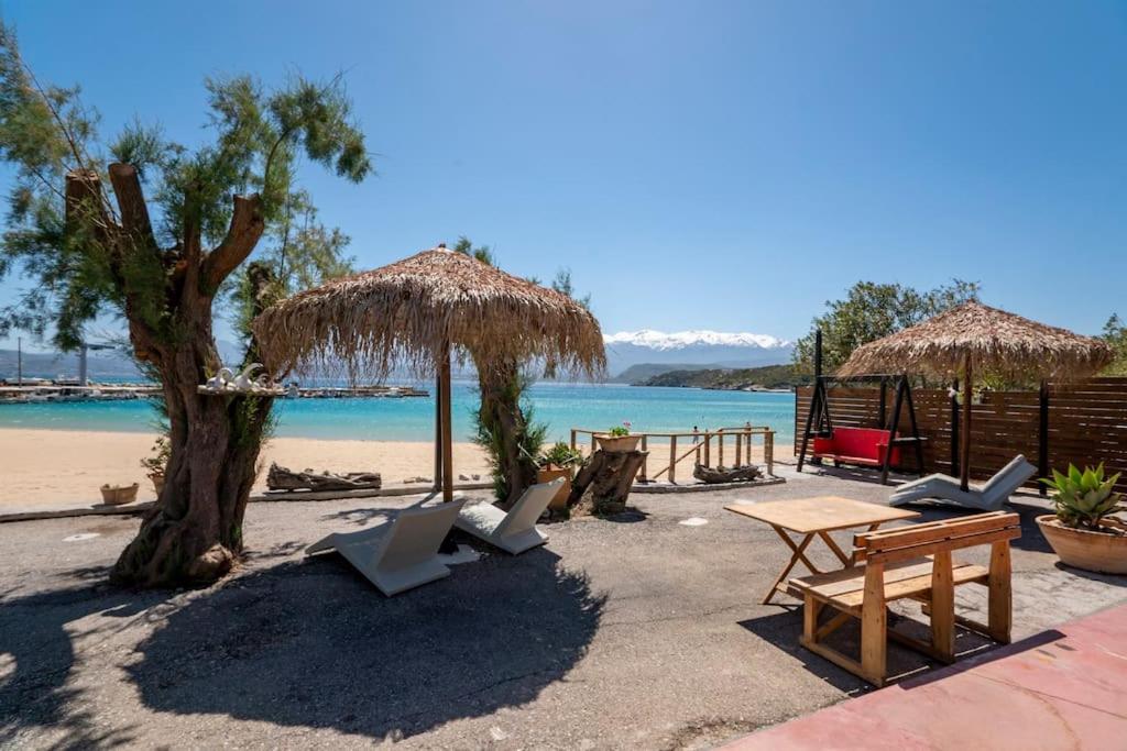 a beach with chairs and a table and straw umbrellas at Sea and Sun Metaxy Mas, brand-new, beachfront ! in Chania