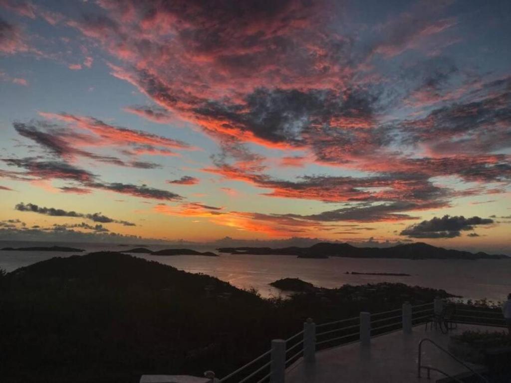 a sunset over a body of water with a fence at Serene Cruz Bay Villa Sep Mstr Kg Suite Stunning Sunsets in Cruz Bay