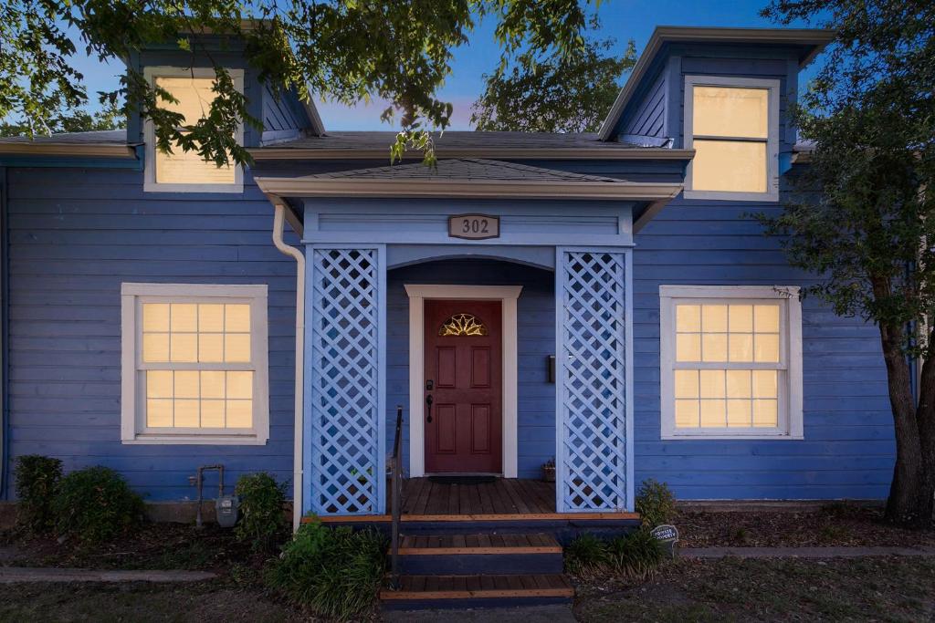 ein blaues Haus mit einer roten Tür in der Unterkunft The Old Downtown Historic Grand Prairie House home in Grand Prairie