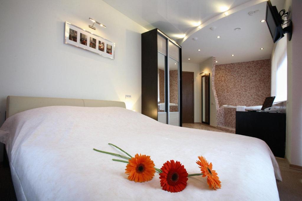 a bedroom with a white bed with two flowers on it at Vorobei Hotel in Nizhny Novgorod