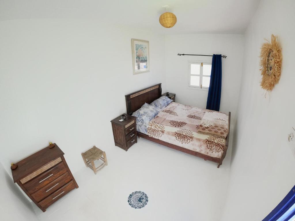 1 dormitorio con cama y ventana en Thayri Hostel en Sidi Kaouki