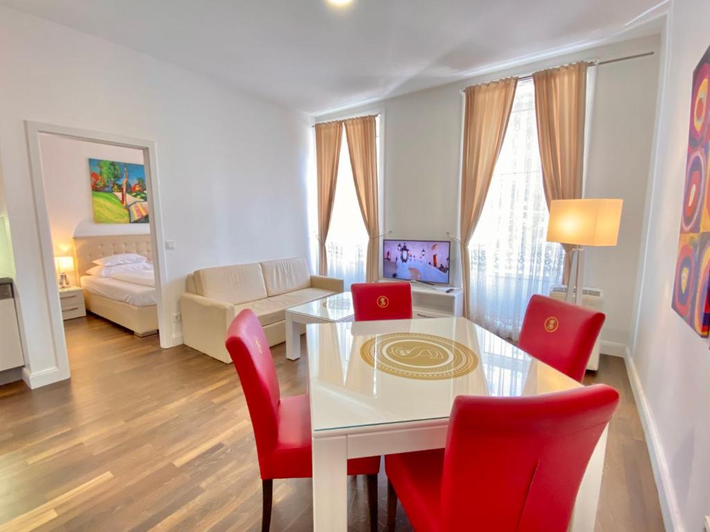 a living room with a white table and red chairs at Steiner Residences Vienna Augarten in Vienna