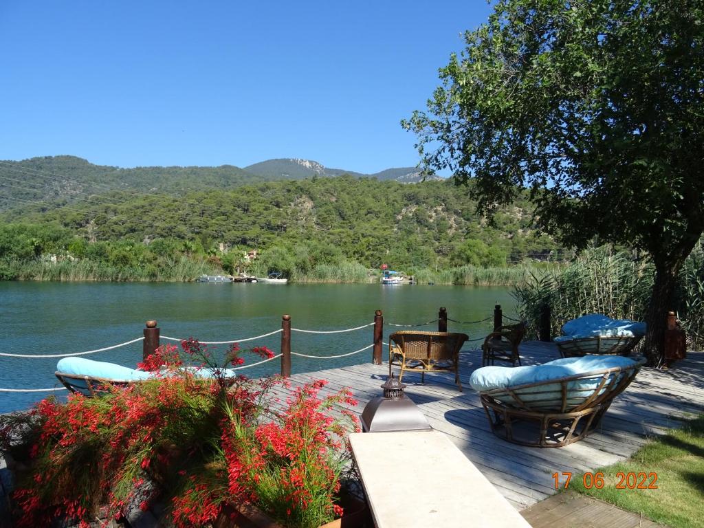 a wooden deck with tables and chairs next to a lake at Dalyan Riverside Private Gaia Koru Bungalows with Swimming Pool Adults Only in Ortaca