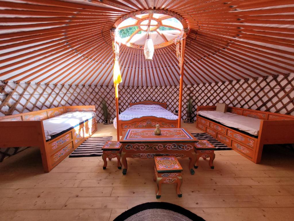 a room with two beds and a table in a yurt at Clos Des Monts in Saint-Martin-des-Besaces