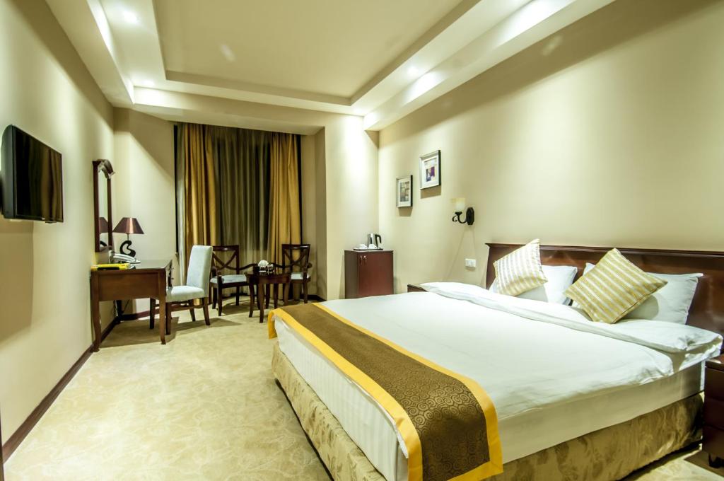 Cette chambre comprend un grand lit et un bureau. dans l'établissement Diamond Hotel Yerevan, à Erevan