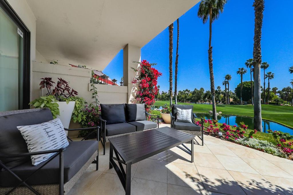 Un patio con sillas y una mesa y una piscina. en Palm Valley Full Access to Golf, Tennis, and Pickle Ball- Luxury 3 King Beds 3 Full Baths, en Palm Desert