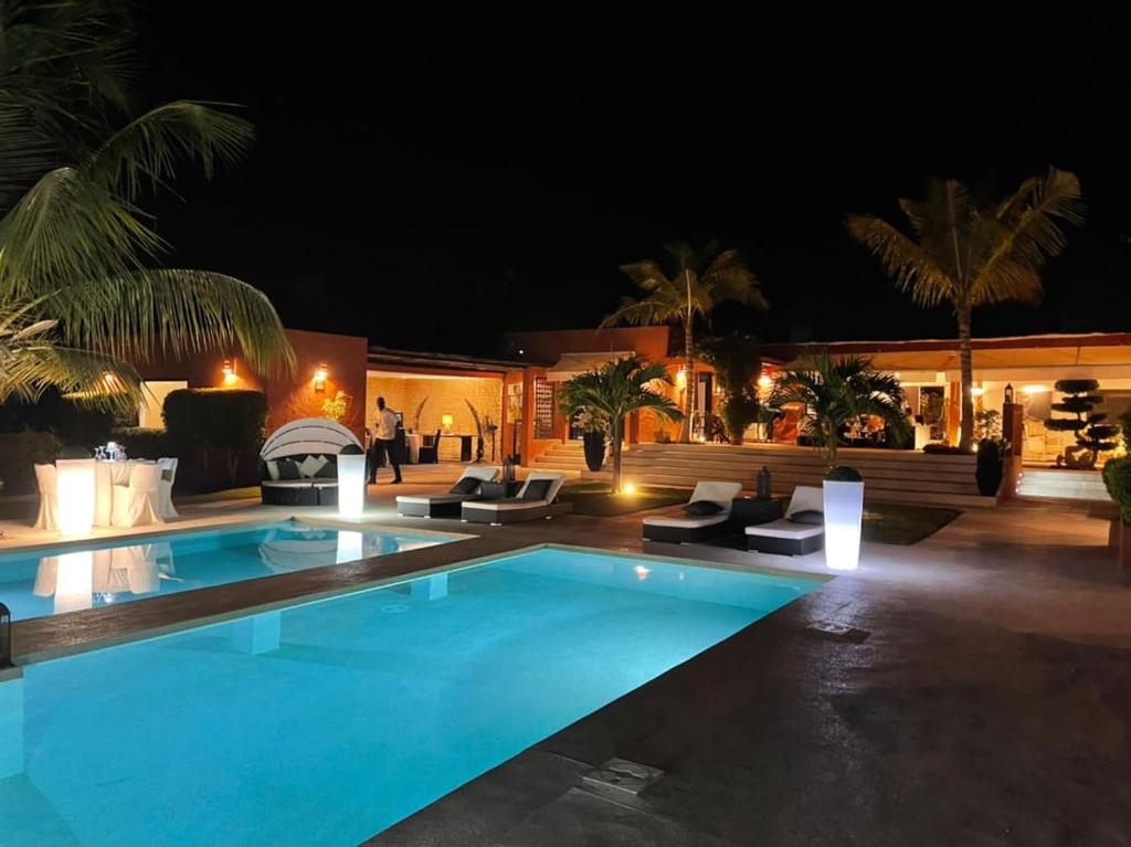 a swimming pool at night with chairs around it at Villa Le Petit Paradis Saly Boutique Hotel in Ngaparou