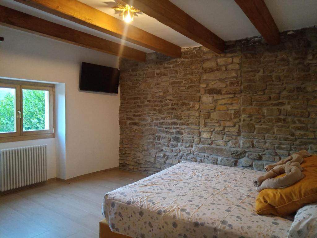 ein Schlafzimmer mit einem Bett und einer Ziegelwand in der Unterkunft Agriturismo Il Regno del Marrone in Castel del Rio